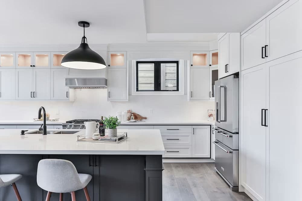Modern kitchen featuring white cabinetry, a large island, and stylish black pendant lighting.